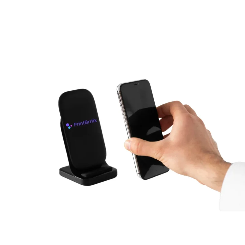 A hand holding a phone on a charging stand.