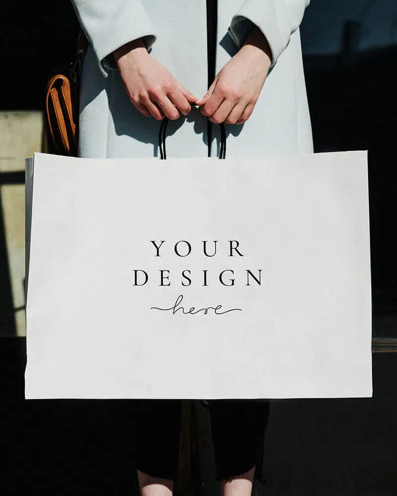 a woman holding a white paper bag with the words your design here